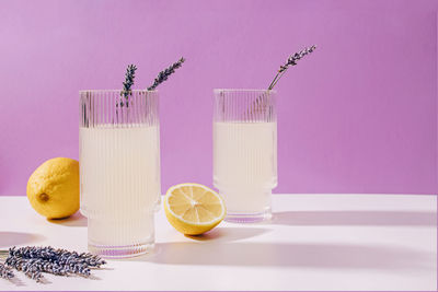 Two ribbed glasses with lavender lemonade over purple background, summer refreshing drink