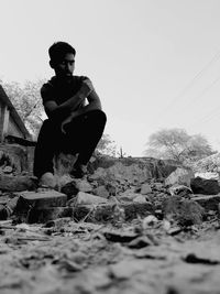 Man sitting on rock against clear sky