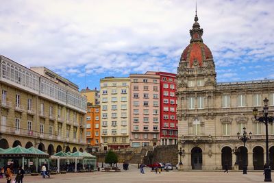 Buildings in city against cloudy sky
