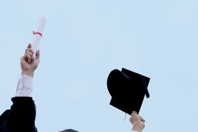 Low angle view of man holding umbrella against sky