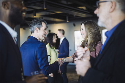 Smiling coworker greeting female entreprenuer with handshake in office