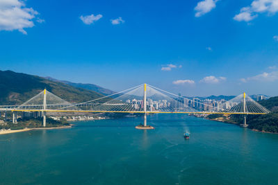 Suspension bridge over sea against blue sky during sunny day