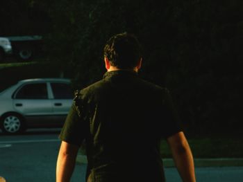 Rear view of man standing in front of car