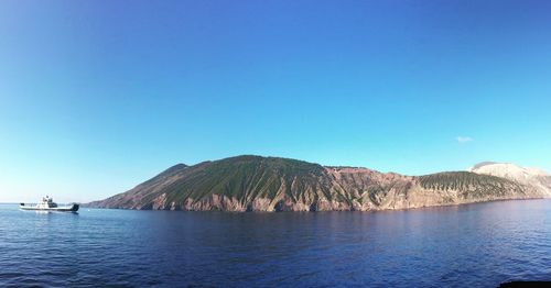 Scenic view of sea and mountains against clear blue sky