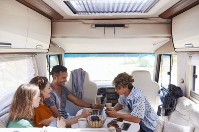 High angle view of family looking at laptop while sitting in camper van