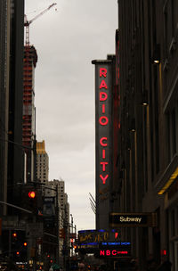 Low angle view of illuminated text on street against buildings in city