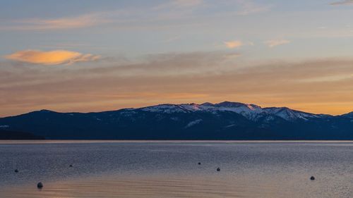 Scenic view of lake and mountains against sky during sunrise