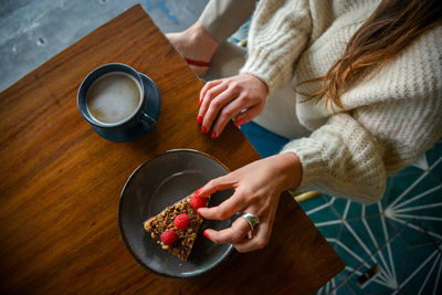 High angle view of woman holding coffee cup on table