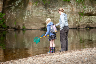 Side view of mother and daughter fishing in lake with nets