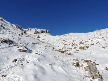 Scenic view of snowcapped mountains against clear blue sky