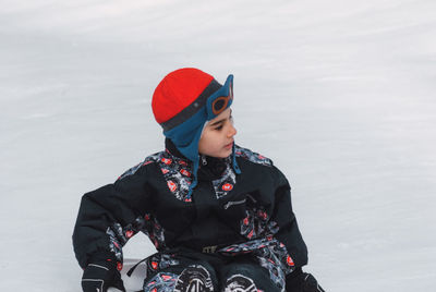 Boy tobogganing on snow covered field during winter
