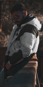 Young man looking away while sitting outdoors