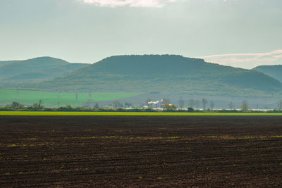 Scenic view of agricultural field by mountains against sky