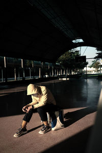 Man wearing hood sitting on luggage