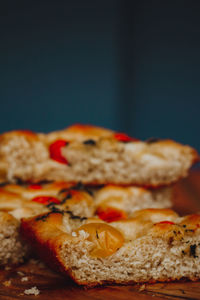 
homemade italian focaccia slices, with tomato and olive oil on a rustic wooden background.