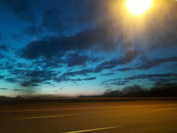 Road by landscape against sky during sunset