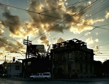 Power lines against cloudy sky at sunset