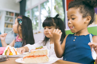 Children eating cake while sitting at home