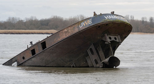 Abandoned boat in lake against sky