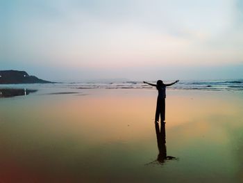 Man standing on beach against sky during sunset