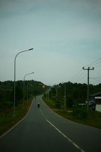 Empty road with trees in background