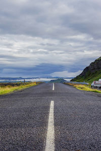 Empty road against cloudy sky