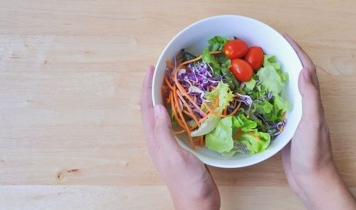 High angle view of hand holding salad in bowl