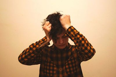 Depressed young man standing against wall