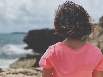 Rear view of girl standing at beach