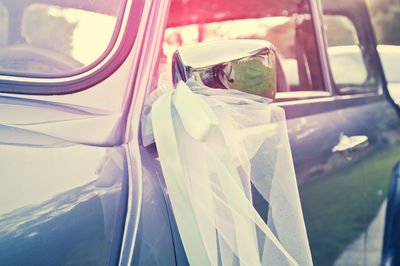 Ribbon bow hanging from side-view mirror of car during wedding ceremony