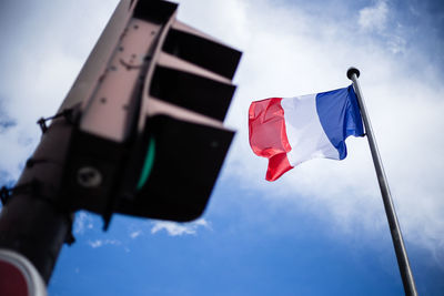 Low angle view of flags and road signal against sky