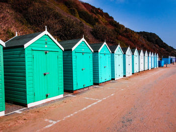 Beach huts by buildings against blue sky