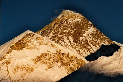 Low angle view of snowcapped mountain against blue sky