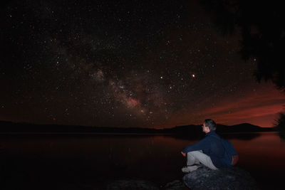 Man sitting at night against sky