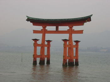 Torii gate amidst sea against sky at itsukushima shrine