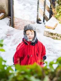 Portrait of smiling boy in warm clothing standing at yard during winter