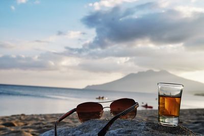 Sunglasses on table at beach against sky