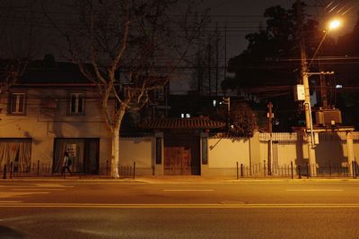 Road by illuminated buildings at night