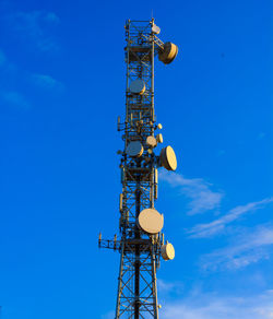 Low angle view of communications tower against blue sky