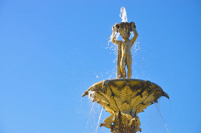 Low angle view of statue against blue sky