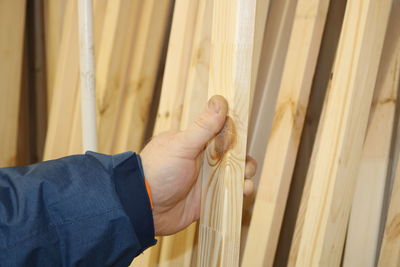 Close-up of man holding wooden plank in workshop