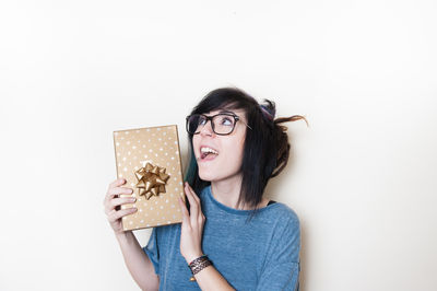Young woman holding eyeglasses against white background