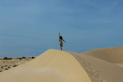 Rear view of woman walking on sand at desert