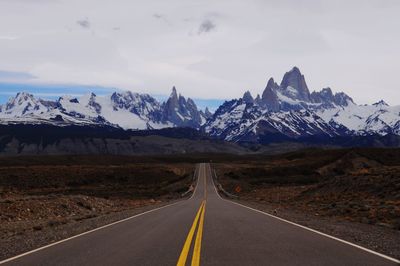 Road leading towards mountains against sky