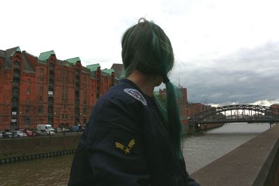 Woman standing in front of city against cloudy sky