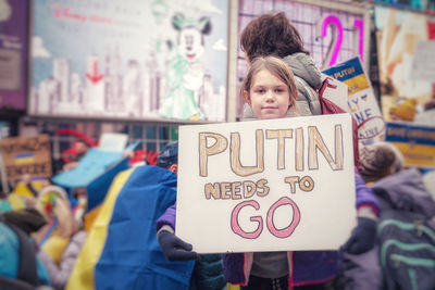 Girl standing with a sign at a protest to support ukraine 