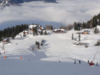 High angle view of people skiing on snow field against cloudy sky