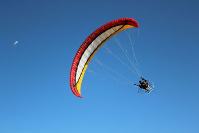 Low angle view of person paragliding against clear blue sky