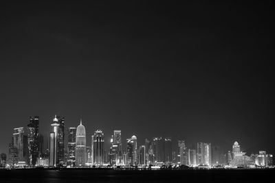 Illuminated skyscrapers against sky at night