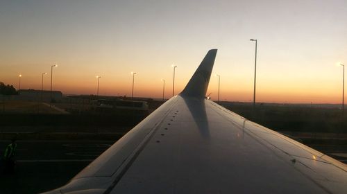 Close-up of airplane on airport runway against sky during sunset